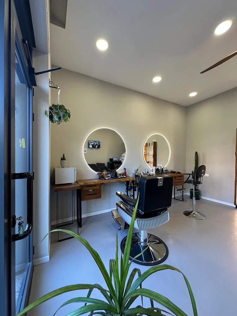 Diseño interior de Feivèr Barber en Treviglio con espejos LED circulares y sillones de barbero.